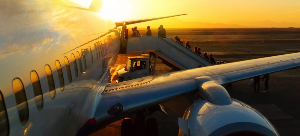 passengers boarding aircraft in airport at sunset