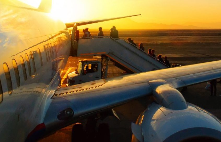 passengers boarding aircraft in airport at sunset